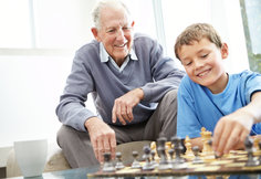A grandfather playing chess with his grandchild