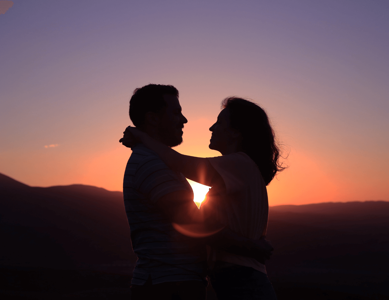 Silhouette of a couple embracing in front of sunset