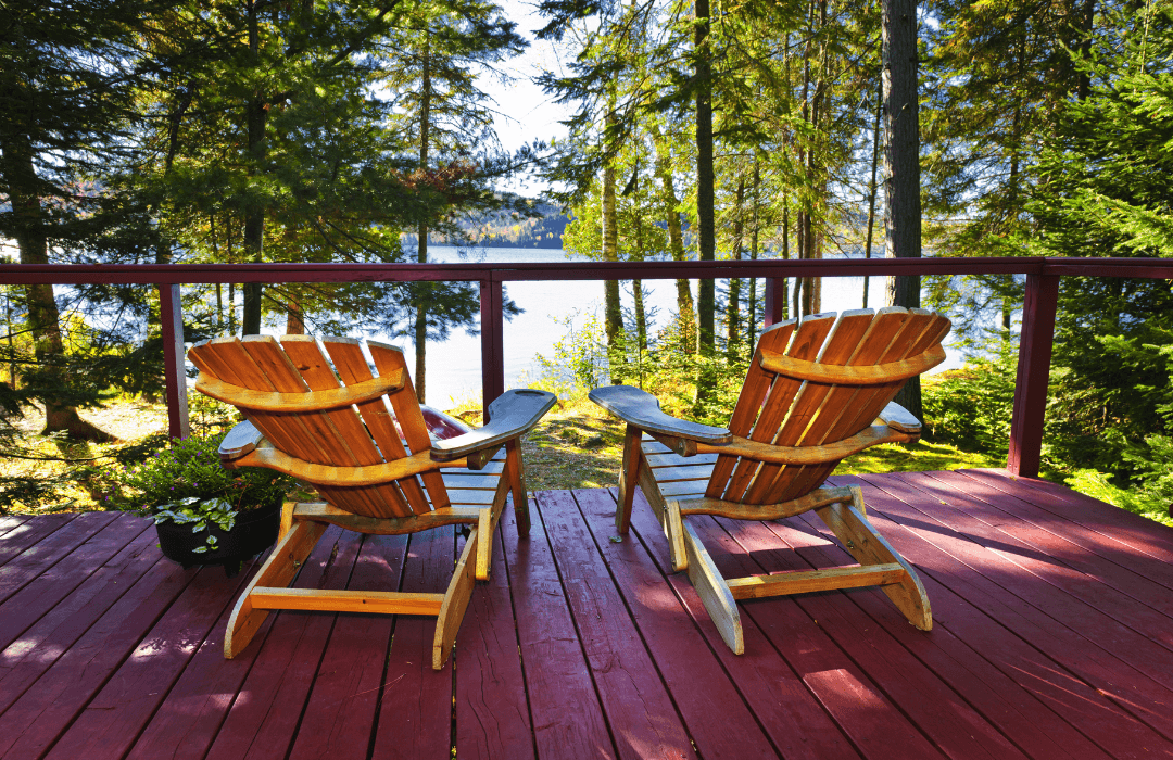 Two chairs on a deck facing a lake